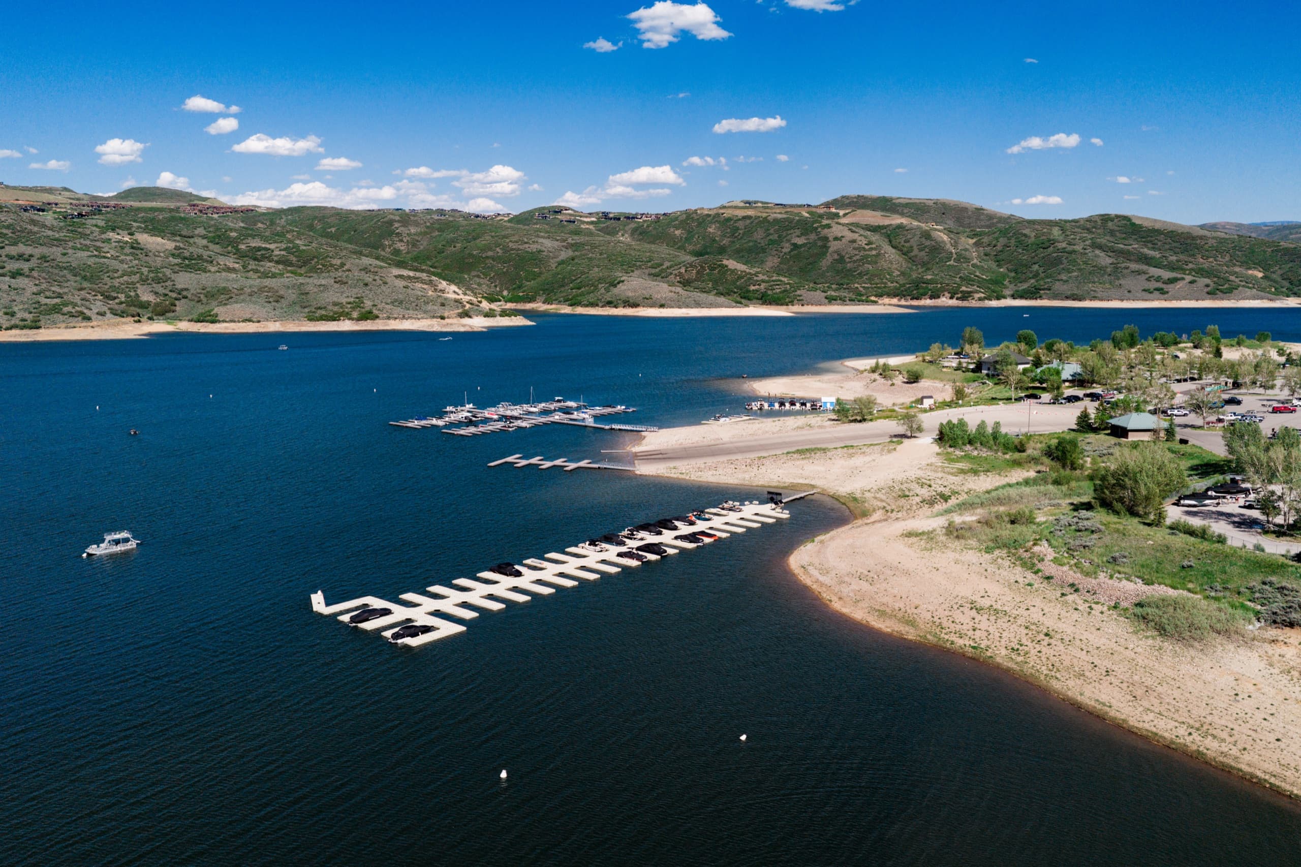 Aerial view of Jordanelle Marina and its boat slips on the reservoir, with the Wasatch mountains and summer clouds behind
